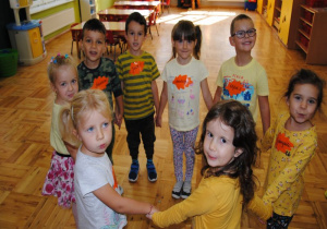 dzieci ubrane w kolorach żółci i zieleni tańczą w kole